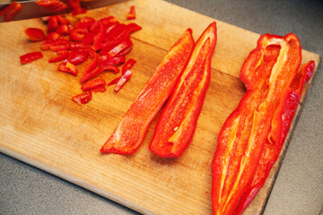 slicing red sweet peppers on wooden board