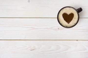 Top view of coffee cup with heart on wooden background