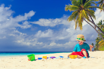 Fototapeta na wymiar little boy building sand castle on beach