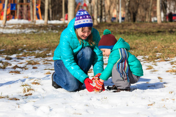 mother and son building snowman in winter