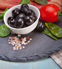 Sliced prosciutto with salad and olive