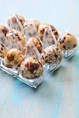 Quail eggs in a transparent plastic container on wooden backgrou