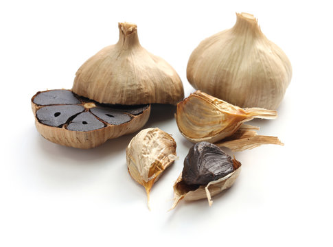 black garlic bulbs and cloves on white background