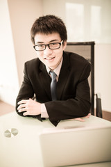 Naklejka premium Young handsome man using laptop in his office
