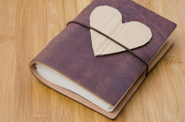 closeup of an old notebook with a cardboard heart on top