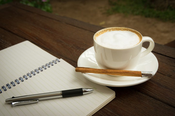Coffee cup with pen and book.