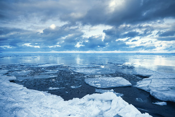 Fototapeta premium Winter coastal landscape with floating melting ice fragments