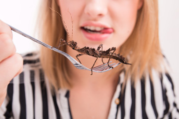 Woman eating insects with a fork in a restaurant