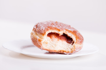 Bitten donut with jam lies on a plate