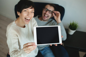 Hipster couple in eyewear showing the screen of tablet