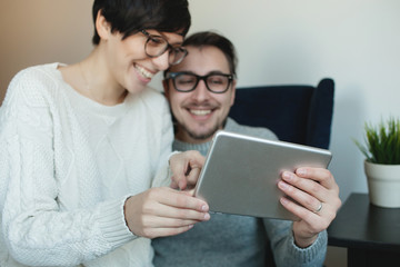 Hipster couple in eyewear enjoying the tablet together