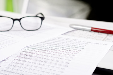 Business composition with laptop glasses pen and statistics shee