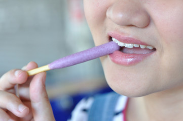 Asian woman eating blueberry snack stick