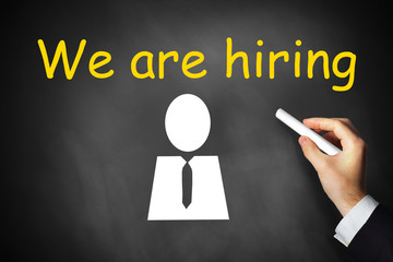hand writing we are hiring on chalkboard employee symbol