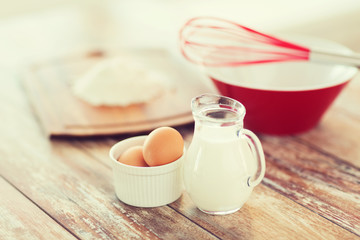 jugful of milk, eggs in a bowl and flour