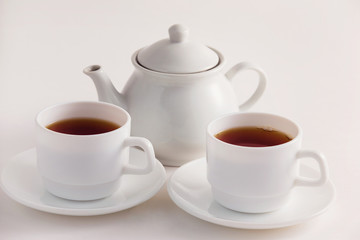 Two tea cups and one teapot with black tea are standing out agai