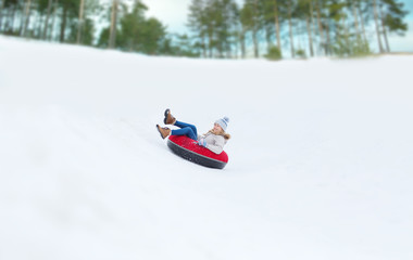 Fototapeta na wymiar happy teenage girl sliding down on snow tube