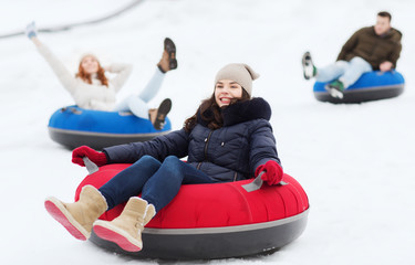 group of happy friends sliding down on snow tubes