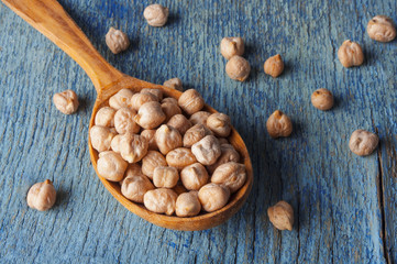 Raw chickpeas in a wooden spoon close-up on an old table
