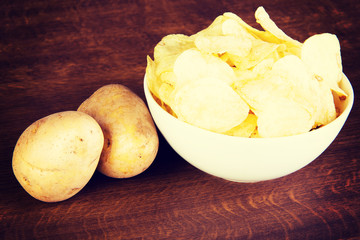 Potatoe chips in a bowl and potatoes.