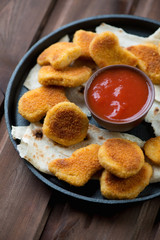 Frying pan with nuggets on pita bread and dip sauce, close-up