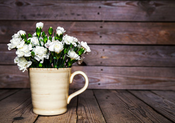 delicate bouquet of carnations in vintage vase with heart on woo