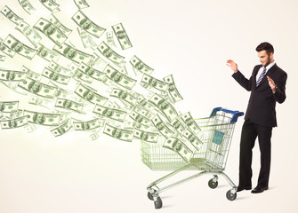 Fototapeta premium Businessman with shopping cart with dollar bills