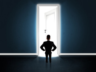Business man looking at big bright opened door