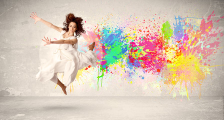 Obraz na płótnie Canvas Happy teenager jumping with colorful ink splatter on urban backg