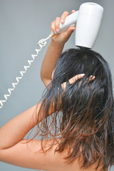 Naklejka premium woman is blowing her hair with hair dryer