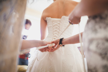 bride's friends help to fit the wedding dress