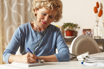 Smiling elderly doctor writes a prescription.