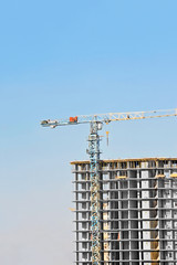 Crane and building construction site against blue sky