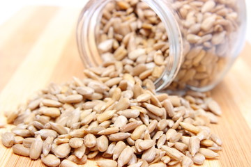 Heap of sunflower seeds in glass jar on wooden cutting board