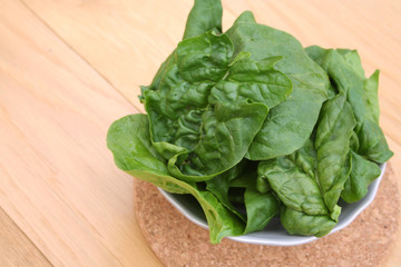 spinaci freschi in foglie su tavolo di legno