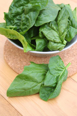 spinaci freschi in foglie su tavolo di legno