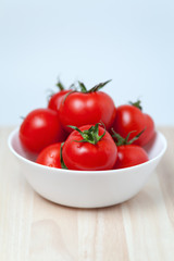 juicy red tomatoes in a bowl on wooden table