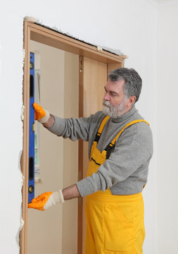 Builder measure verticality of door with level tool, worker