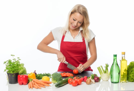 Blonde Hausfrau mit Schürze zerschneidet Tomaten für einen Salat