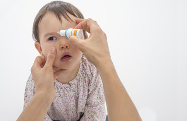 Closeup of mother pouring eye drops in the eye of her daughter
