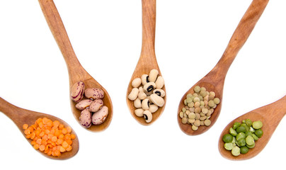 Vegetables on wooden spoons on a white background