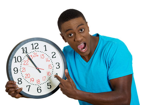 man holding wall clock, stressed pressured by lack of time