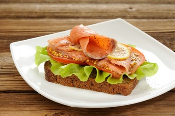Rye bread sandwich with red fish, tomatoes and mustard