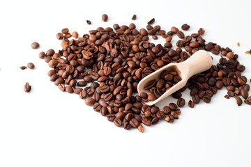 Heap of coffee grains on white board with wooden spoon