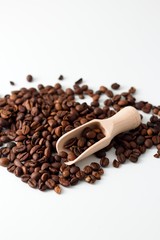 Heap of coffee grains on white board with wooden spoon