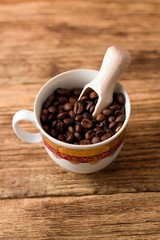 Obraz premium Upper view on cup with coffee grains and wooden spoon