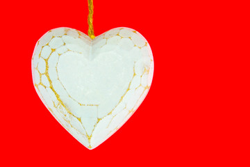 Old worn white wooden heart isolated on red background