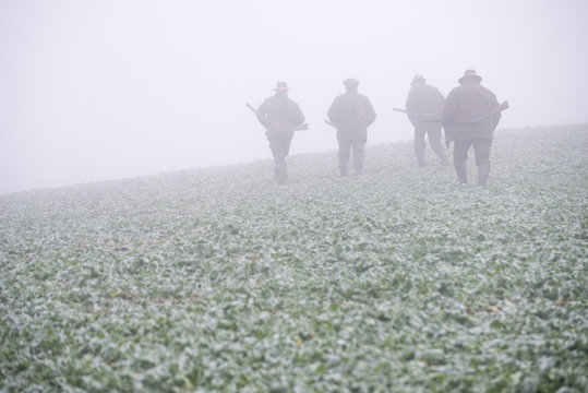 Group of hunters in autumn mist.