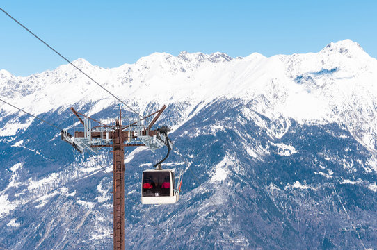 Picture of cable car in front of winter mountains.