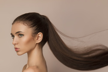 Beautiful woman with long healthy brown ponytail - obrazy, fototapety, plakaty